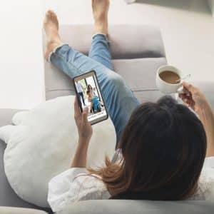 Young woman using smartphone at cozy home on sofa in living room